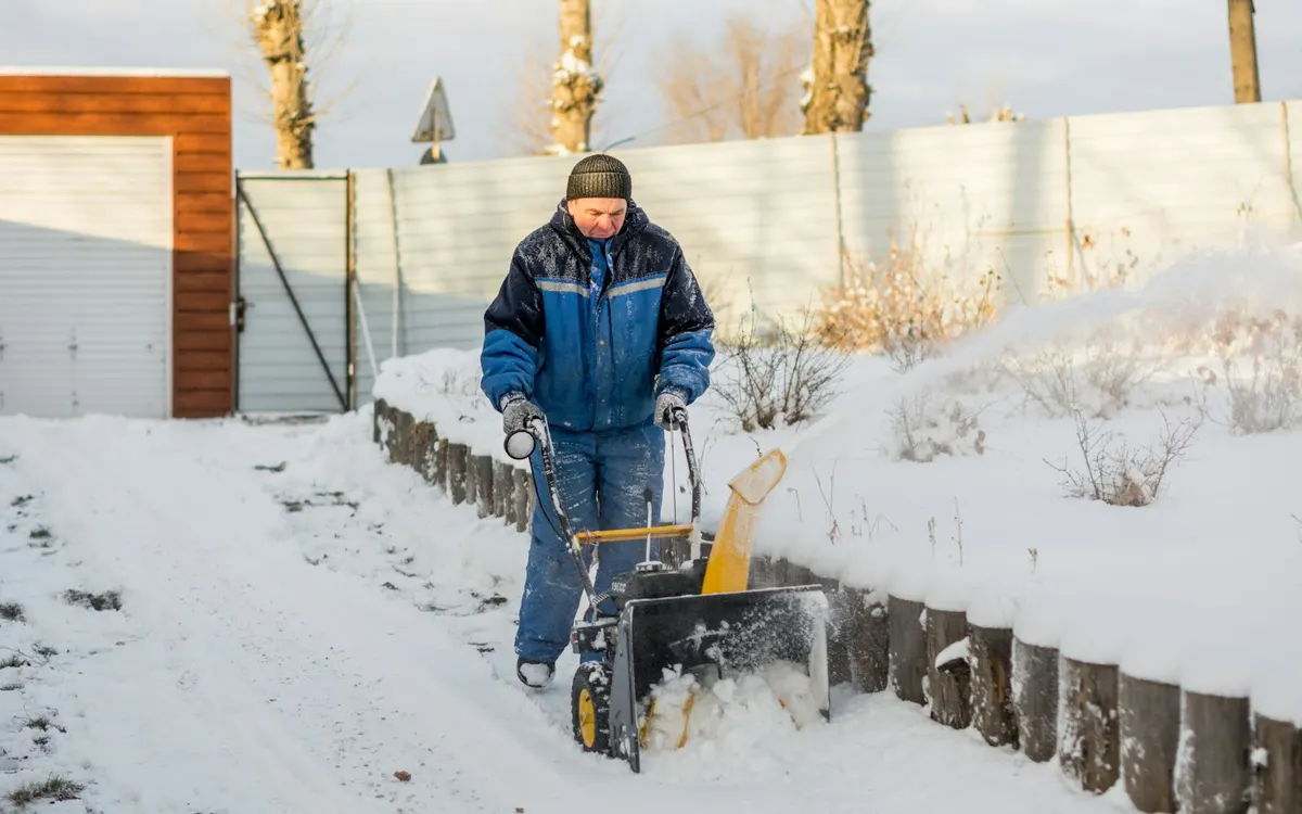 Clearing snow from a sidewalk with a snow blower