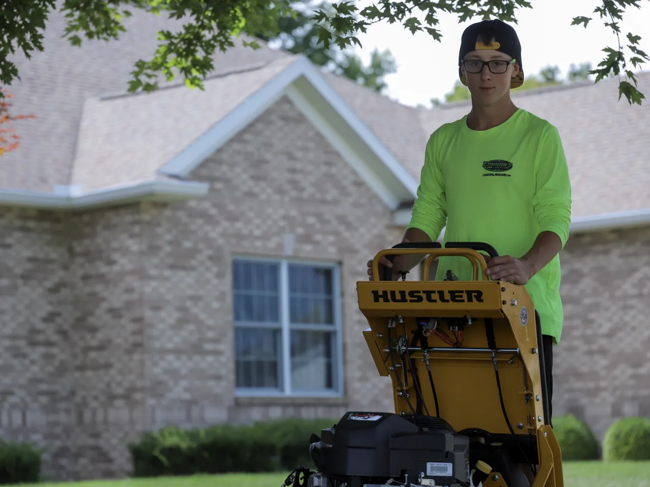 Landon's Lawn Care operator mowing a residential property with a Hustler mower