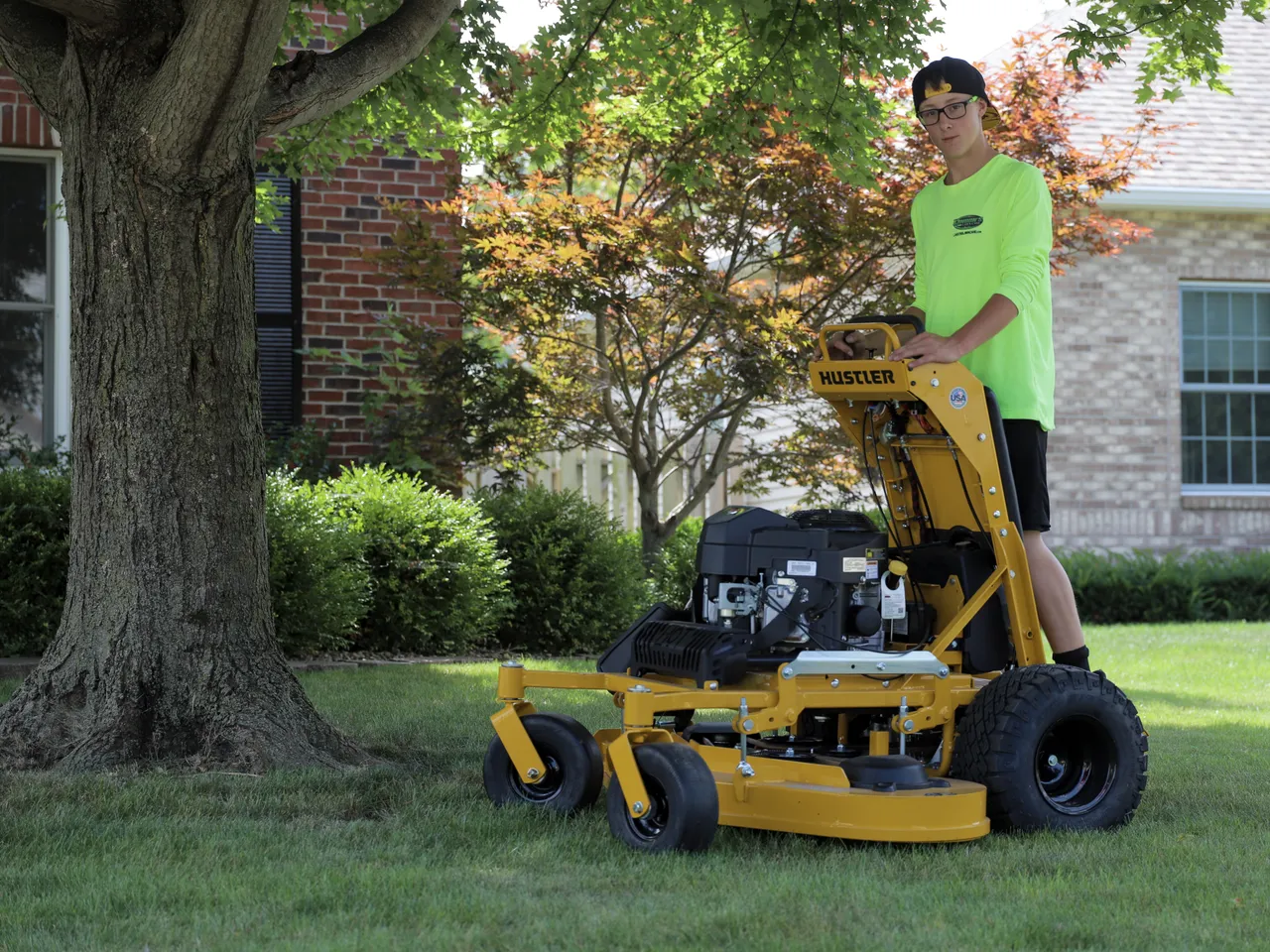 Landon's Lawn Care team member with a mower beneath a large shade tree